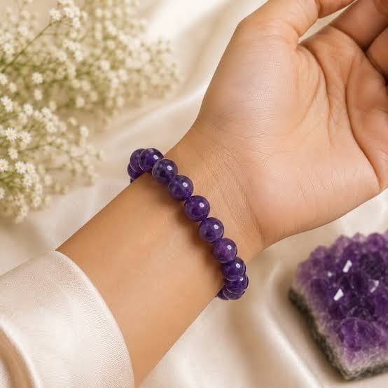 Natural Amethyst bracelet worn on the wrist beside an amethyst cluster