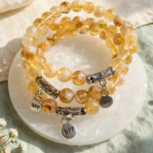 Golden crystal bracelets with BFF charms on a selenite plate