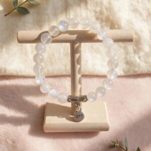 Natural Rainbow Moonstone bracelet with 8 mm blue flash beads and BFF charm on a wooden stand