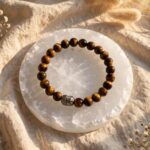 Natural Tiger's Eye bracelet with 8 mm golden brown beads and silver Buddha bead on a selenite plate